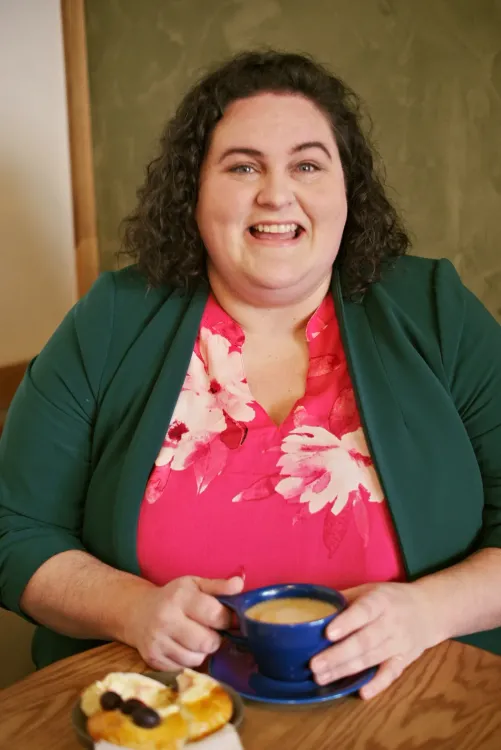 A portrait image of Alicia wearing a pink shirt and green cardigan.